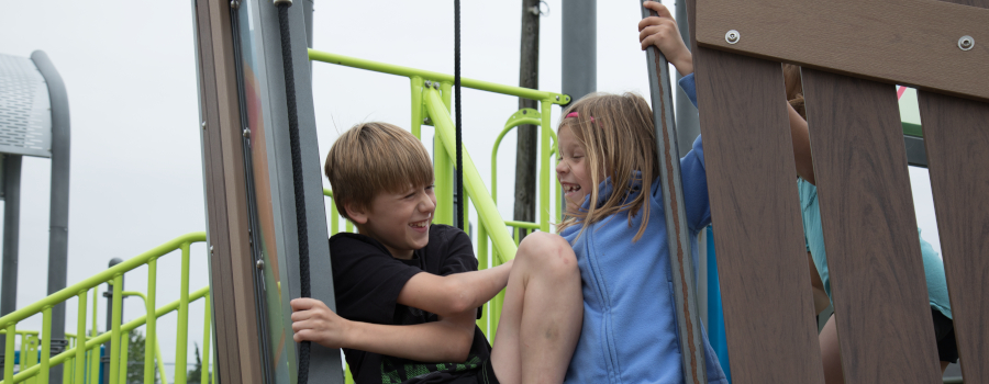 A young boy and girl engaged in social play on the playground