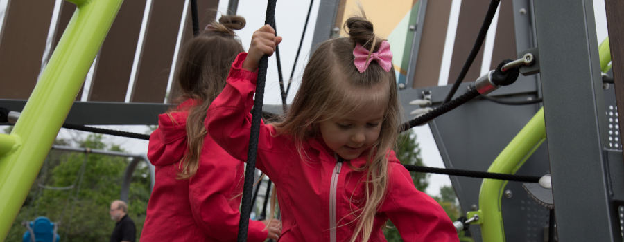 Two girls playing on a playground rope structure
