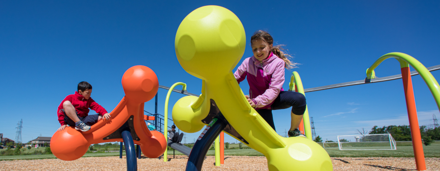 A young girl and boy playing on playground climbers