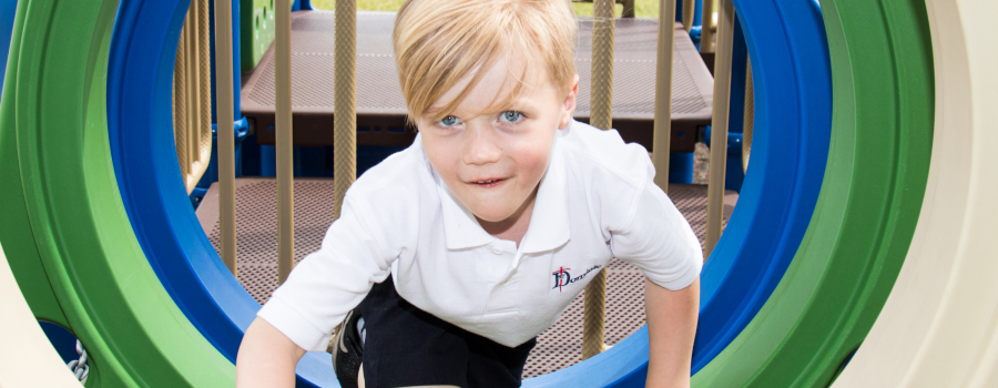 Young boy climbing through a play structure